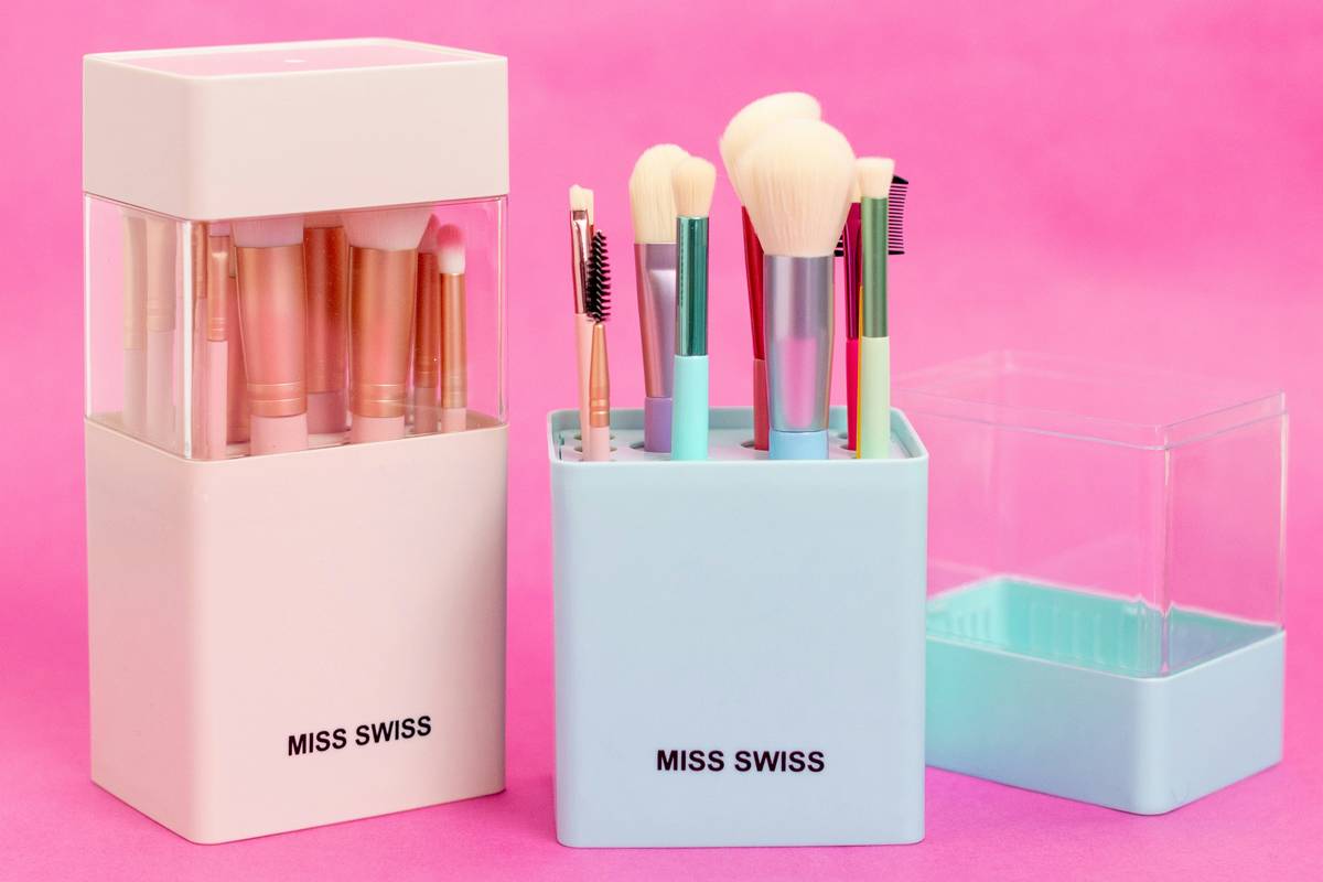 A sleek acrylic makeup storage shelf holding organized lipsticks, eyeshadow palettes, and brushes with natural light